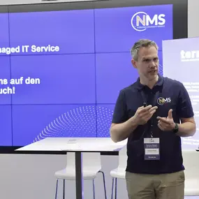 Referent beim Managed-IT-Service-Symposium vor großer Präsentationswand