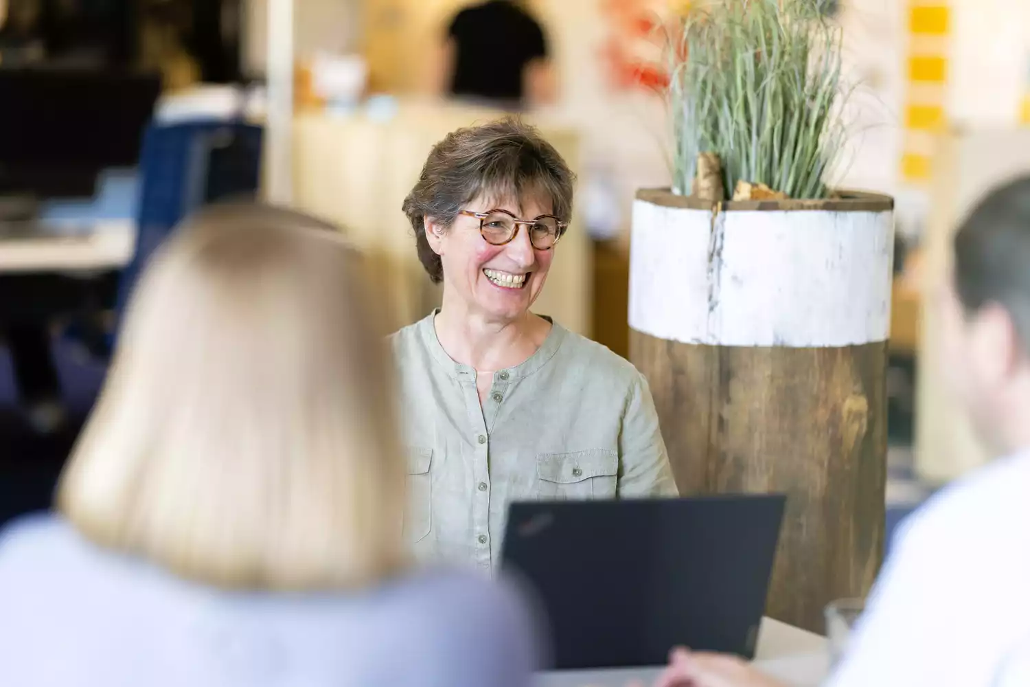 Lachende Frau im Büro-Meeting mit Laptop, Teamgespräch im Coworking Space